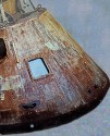 partial image of an early space capsule looking interestingly rusty, with shiny brass-looking handles and rivets.